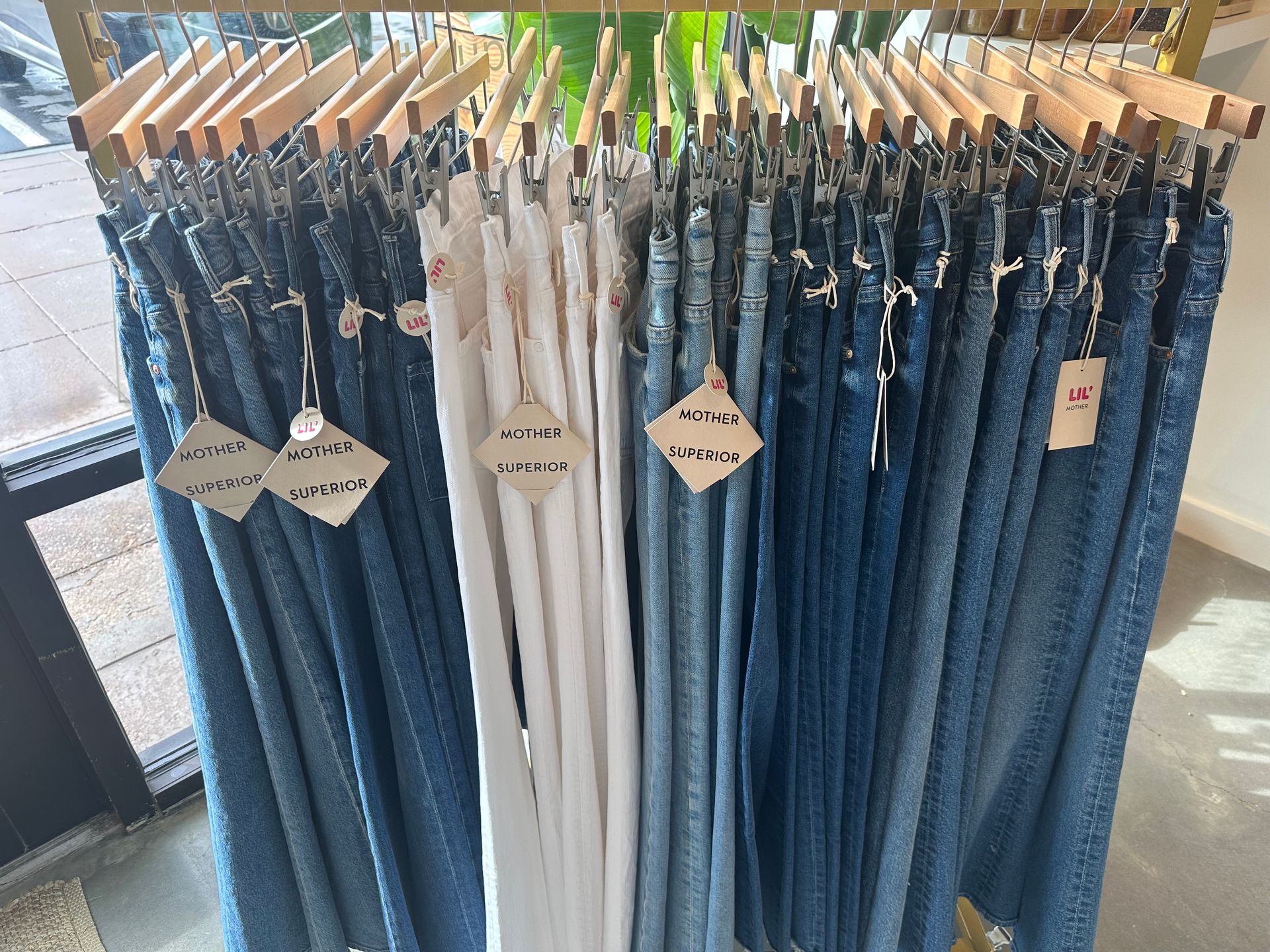 Racks of blue and white jeans hanging on wooden hangers in a clothing store