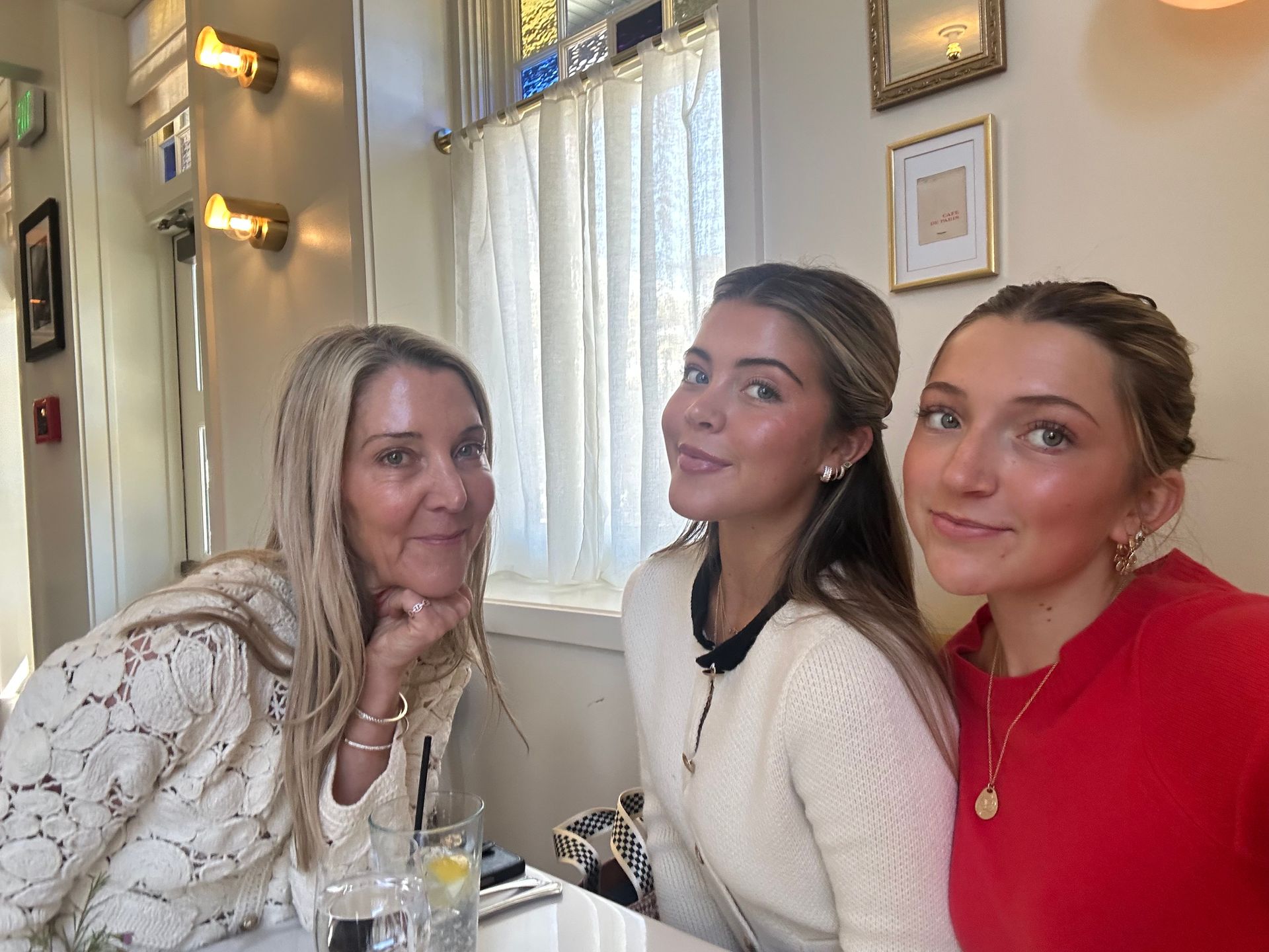 Three people sitting at a table in a cozy restaurant, smiling toward the camera.