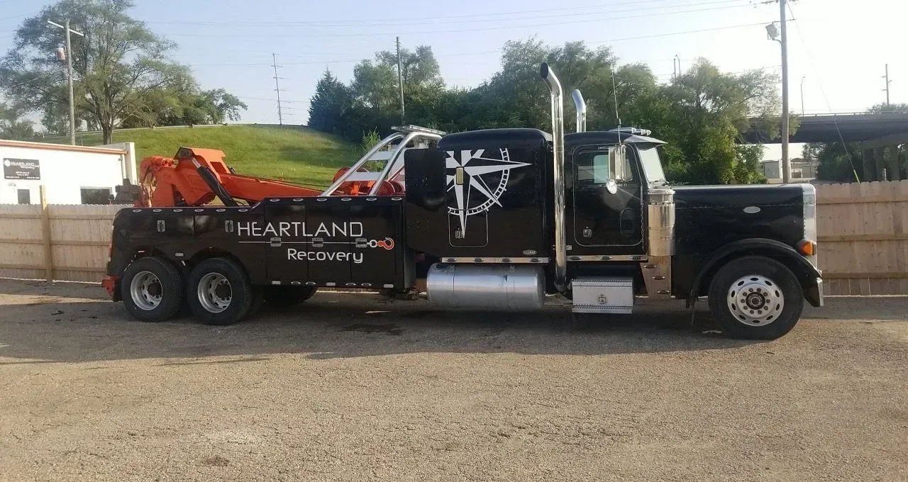 A black tow truck with orange equipment and 