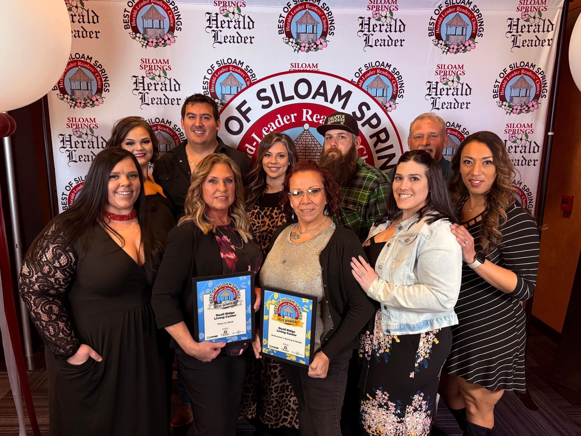 Group of people holding awards in front of a backdrop that says