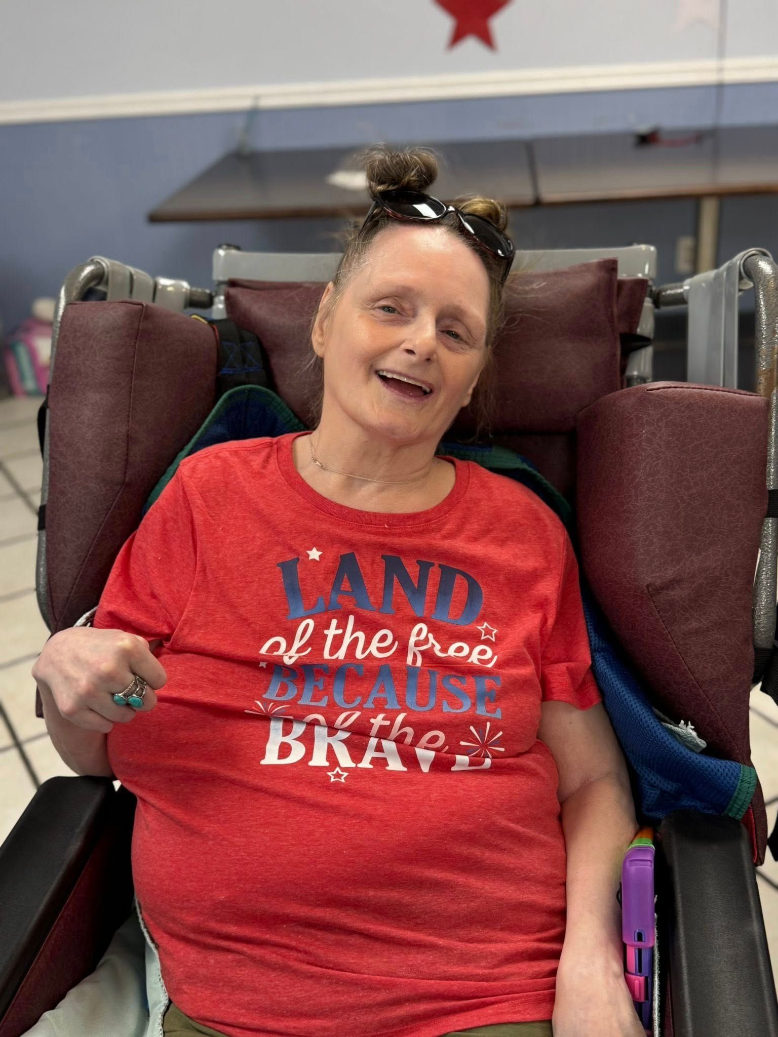 Woman in a wheelchair, smiling, wearing a red