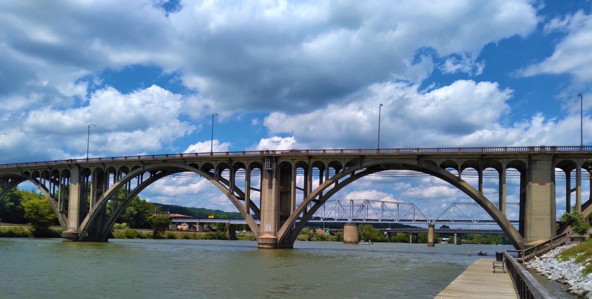 Stone arch bridge over a wide river under a cloudy blue sky Stone arch bridge over a wide river under a cloudy blue sky