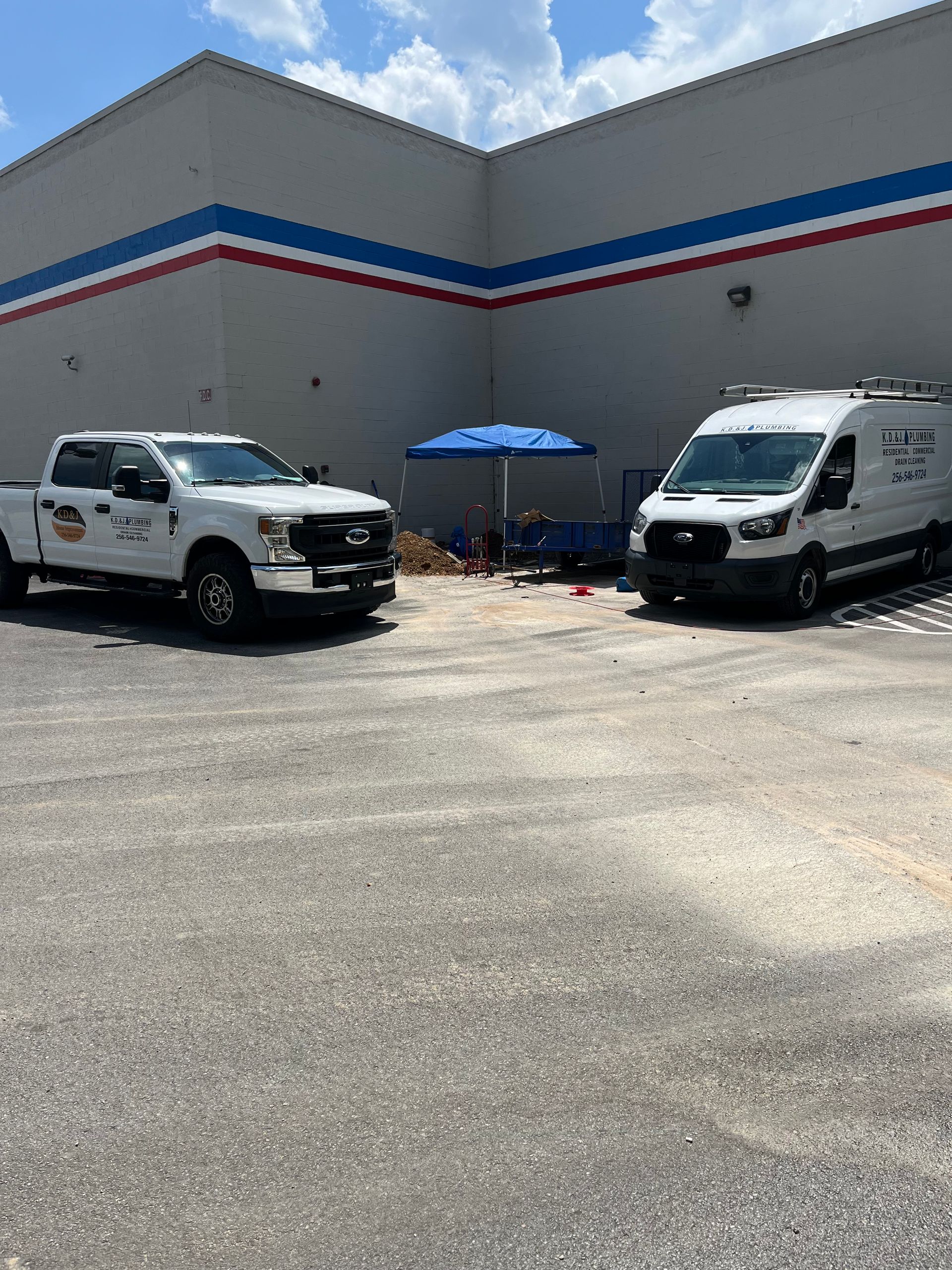 White utility truck and white van parked by a building wall under a blue umbrella on a sunny day White utility truck and white van parked by a building wall under a blue umbrella on a sunny day