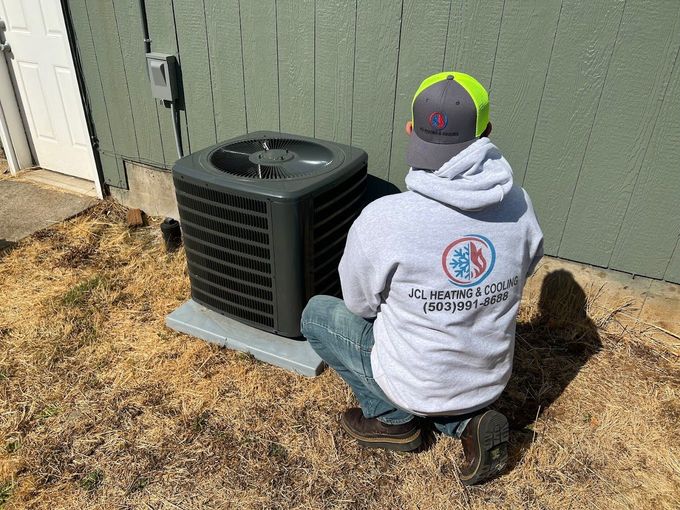a man is sitting on the ground next to an air conditioner .