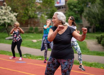 a group of older women are dancing in a park .