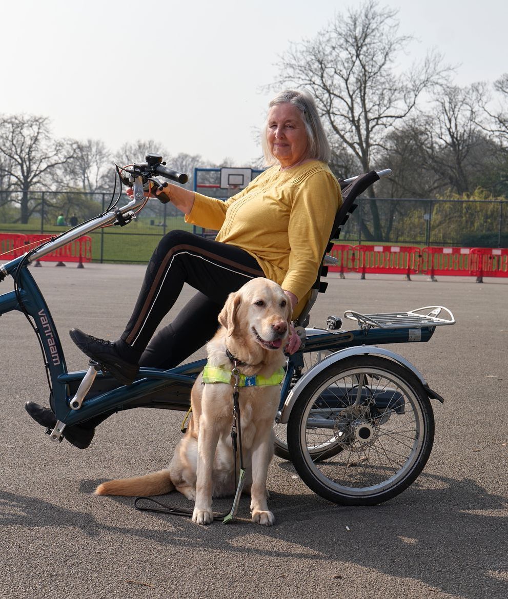 a woman is sitting on a bicycle with a dog sitting next to her