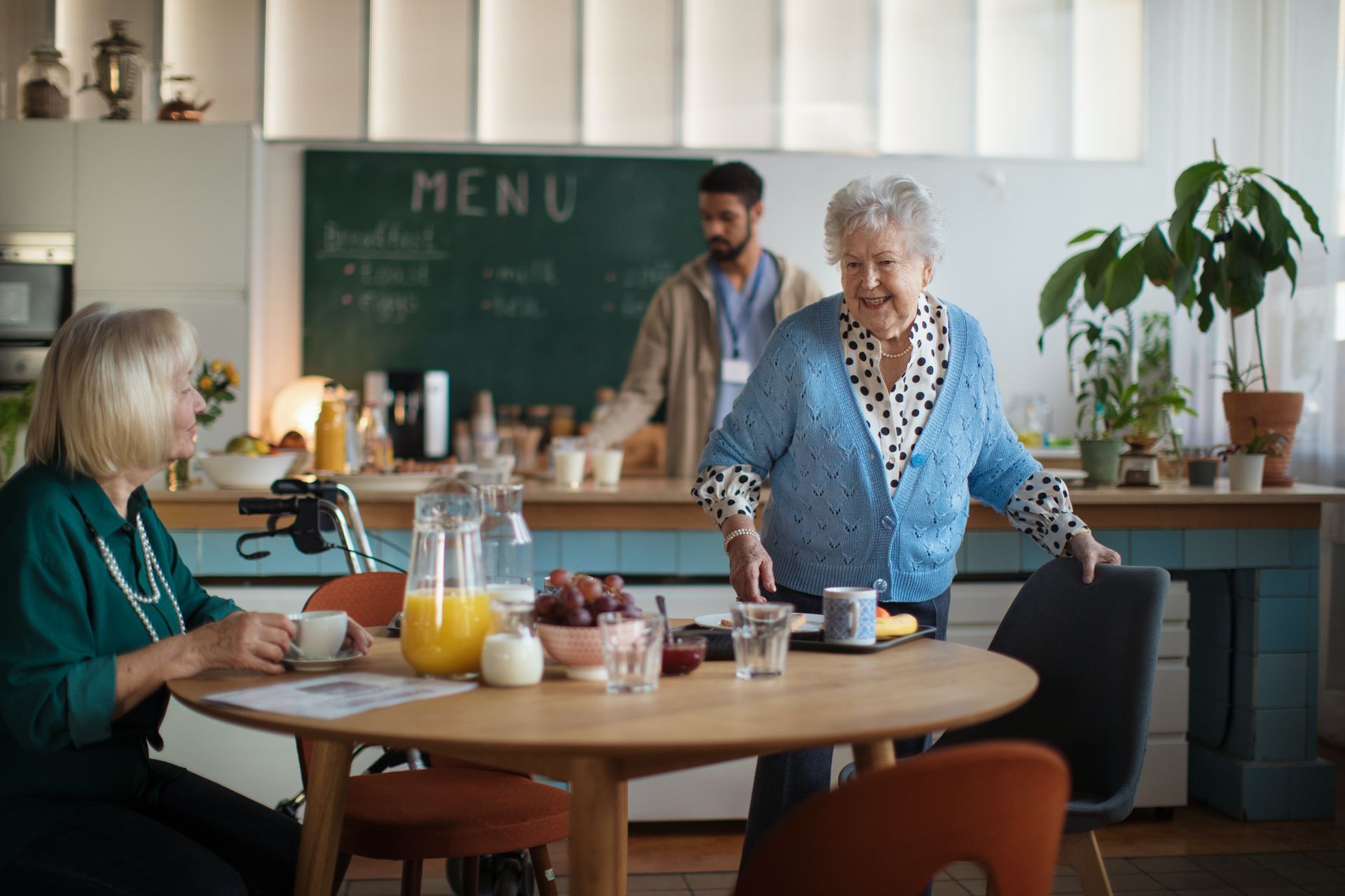 a group of elderly women are sitting at a table in a kitchen .