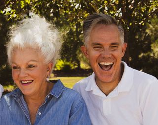 a man and a woman are laughing together in a park .