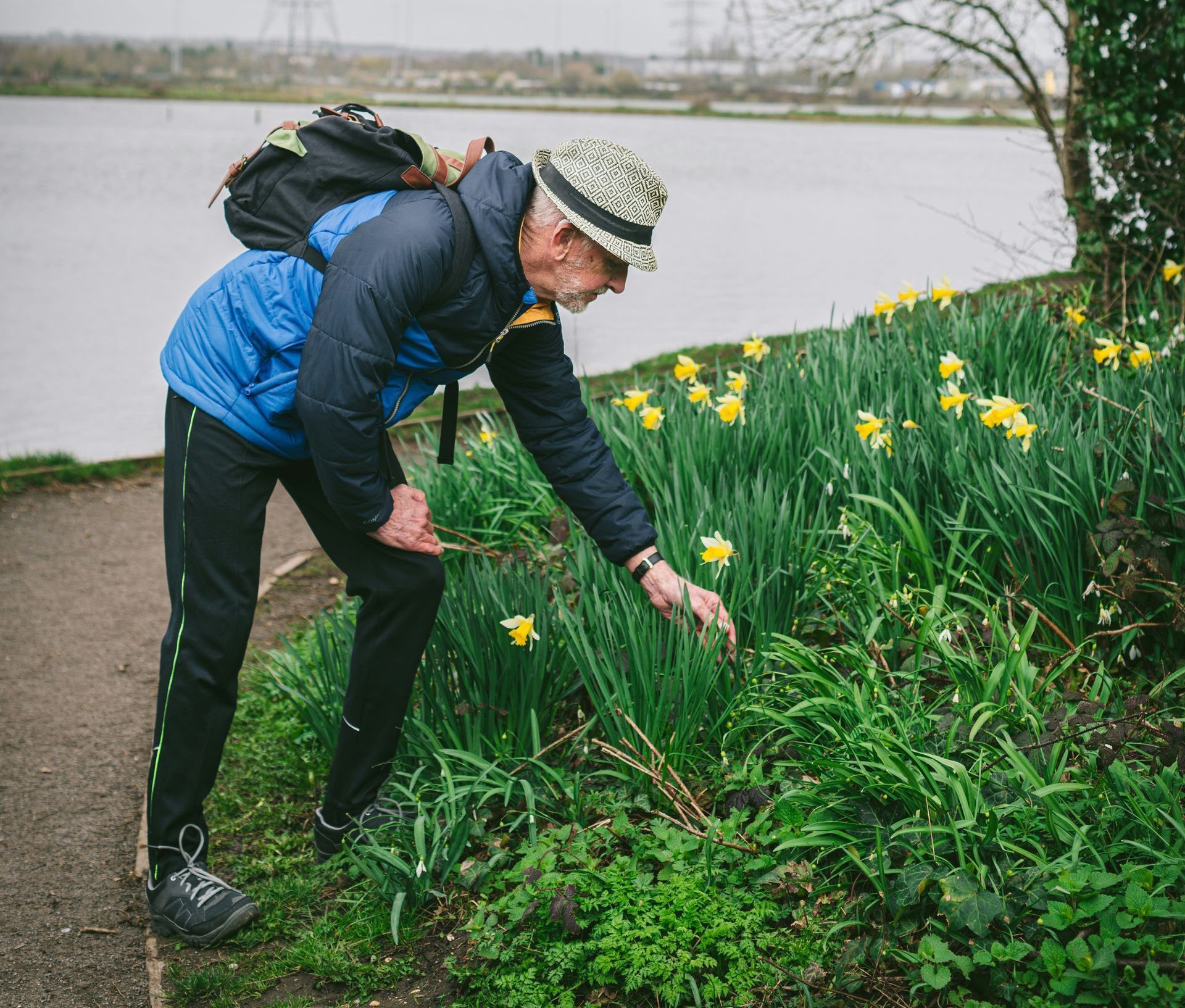 a man in a hat is picking flowers in a garden .