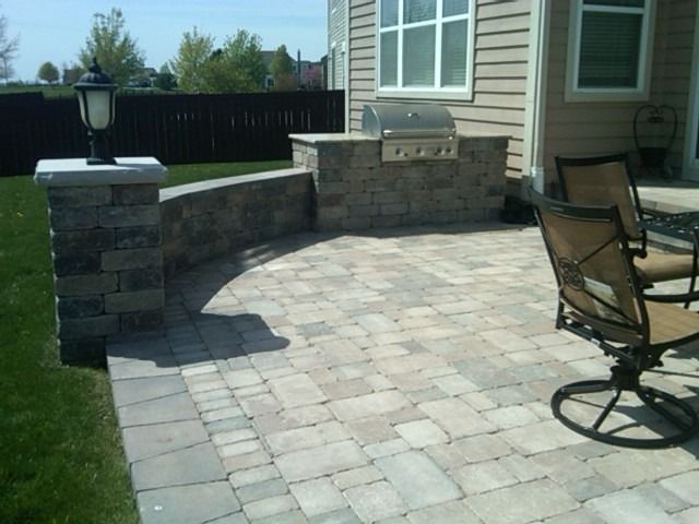 Patio with built-in grill, stone pavers, surrounding wall, and outdoor seating.