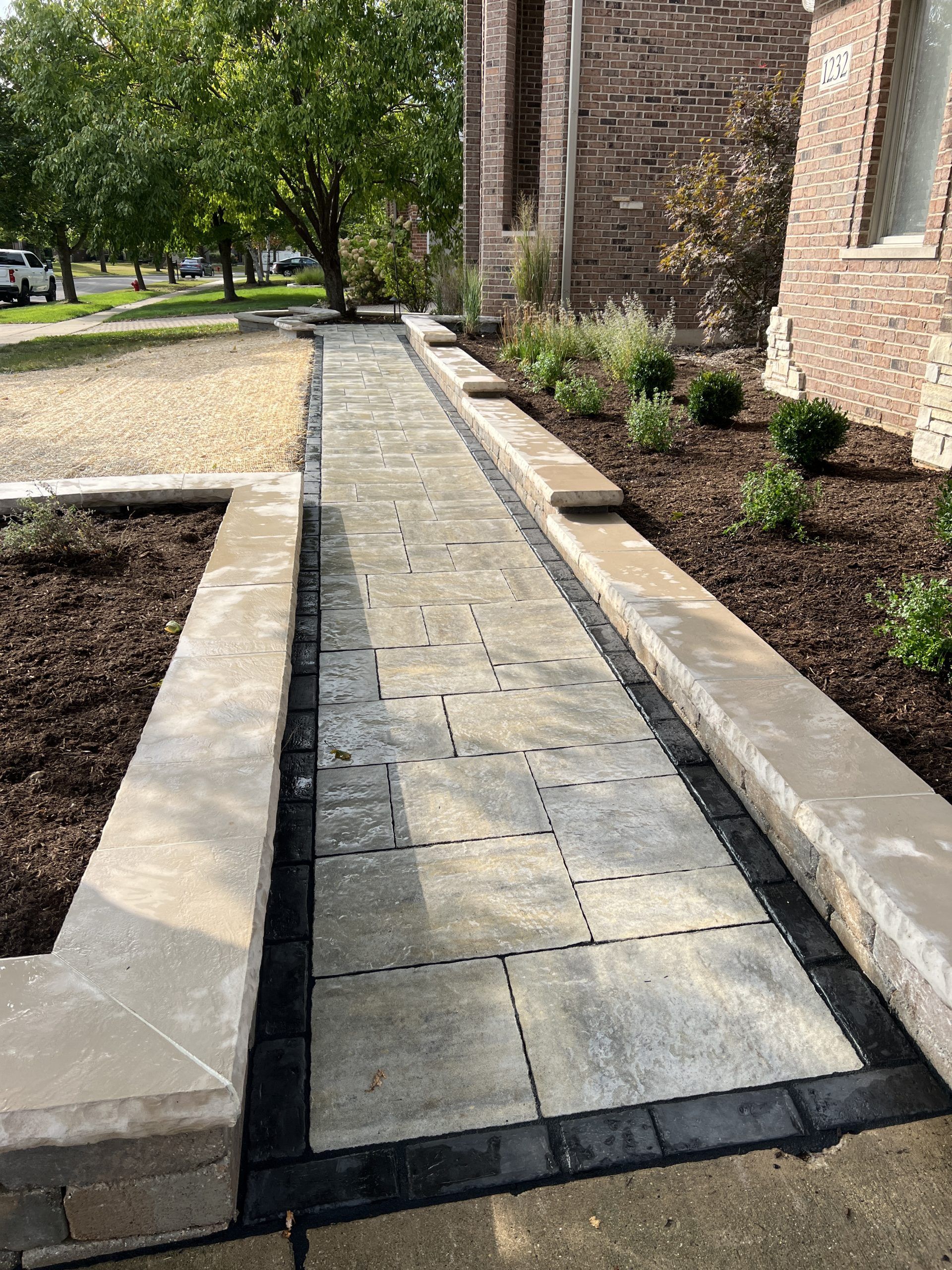 Stone pathway with low retaining walls on either side, leading to a brick building.