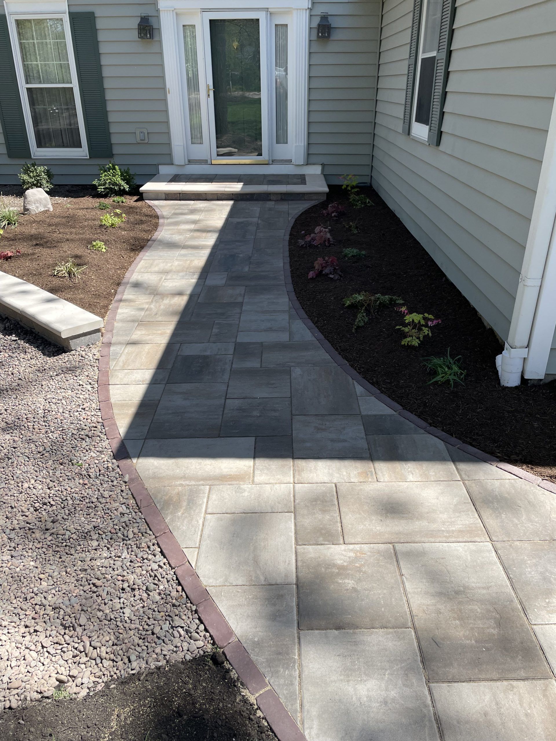 Stone walkway curving to a home's front door, lined with mulch and plantings.