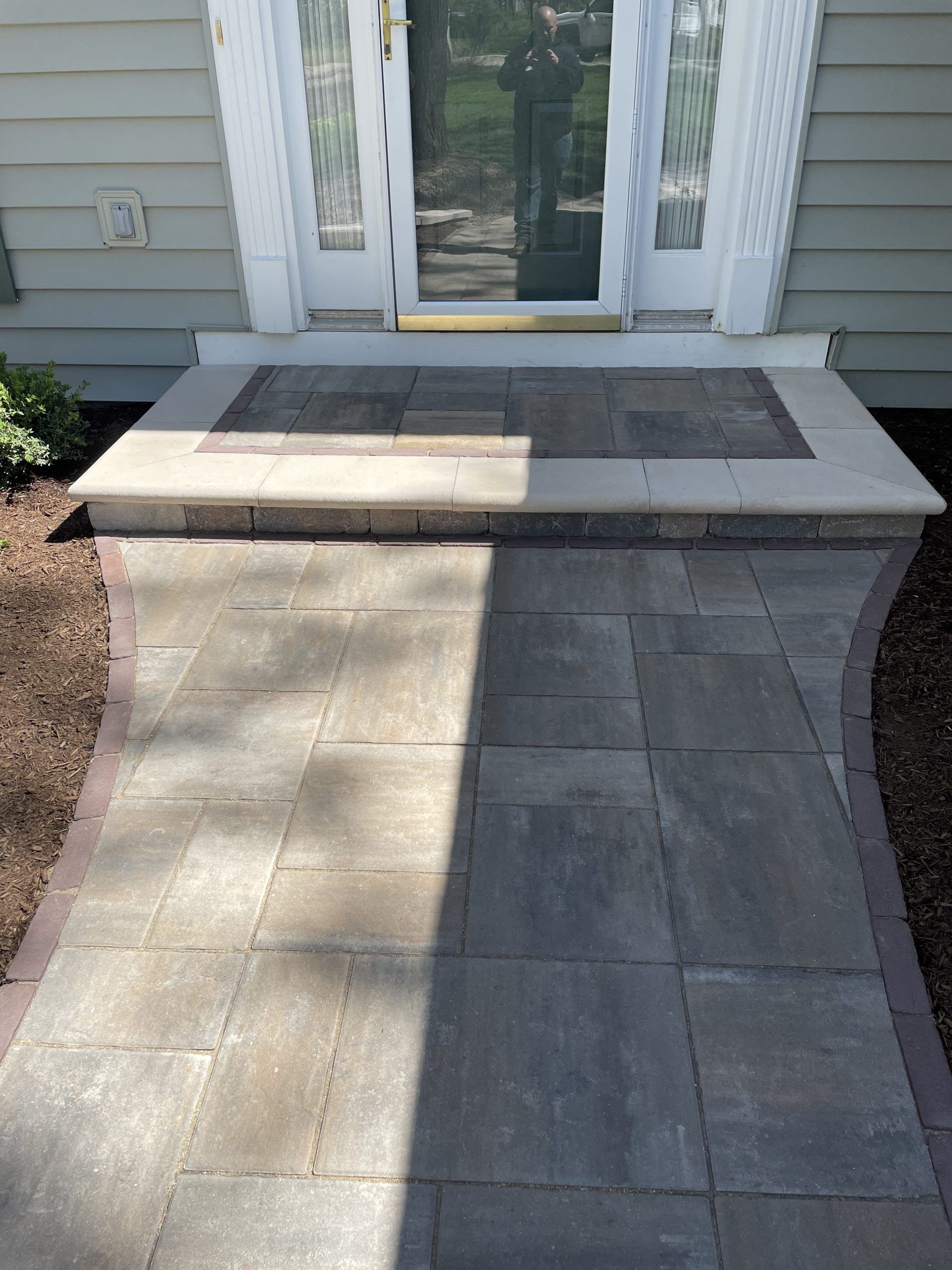 Paver walkway leading to a front door with a small step and stone landing.