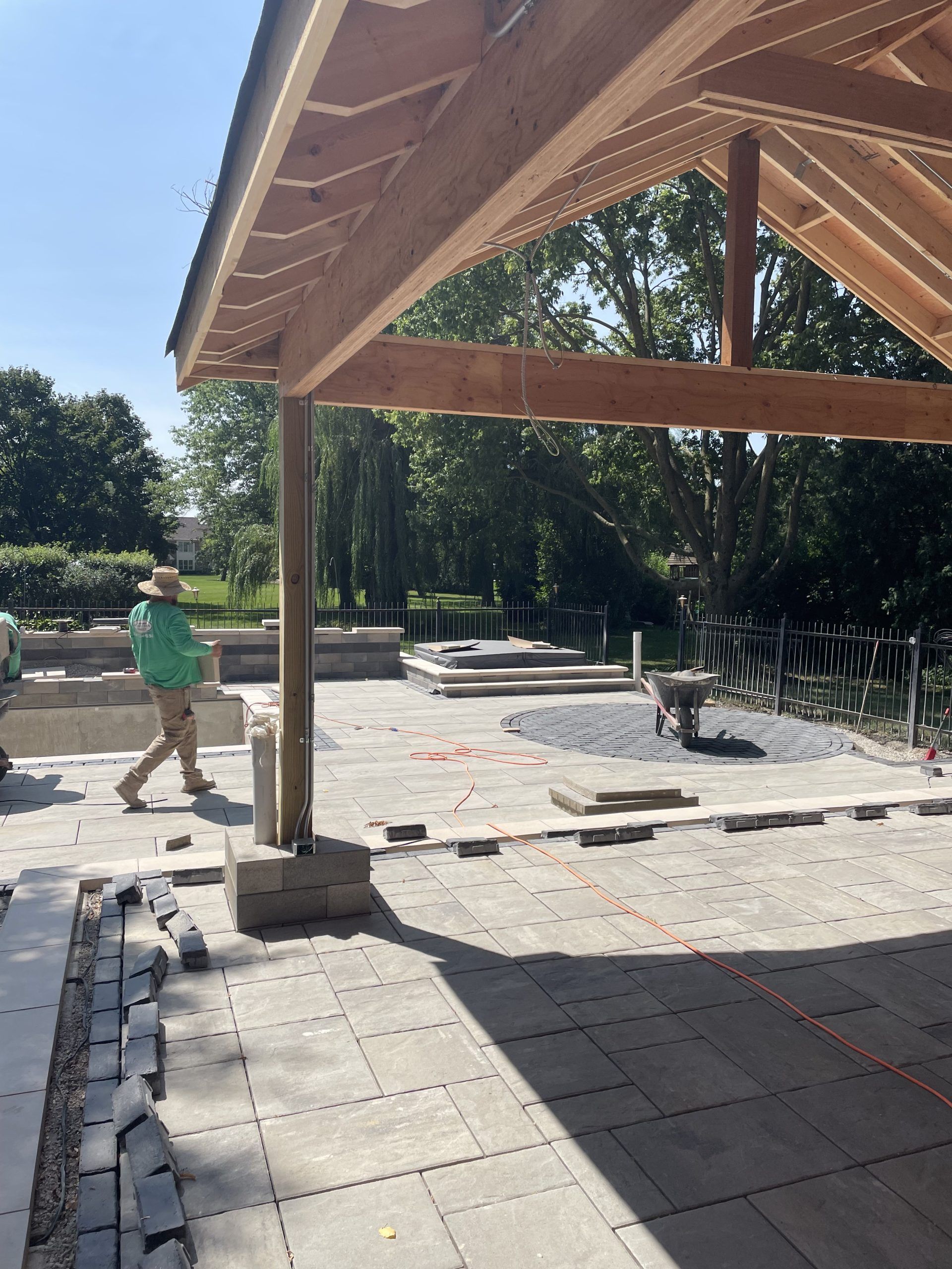 Construction of a patio and roof: A worker in green walks past a partially built wooden structure.