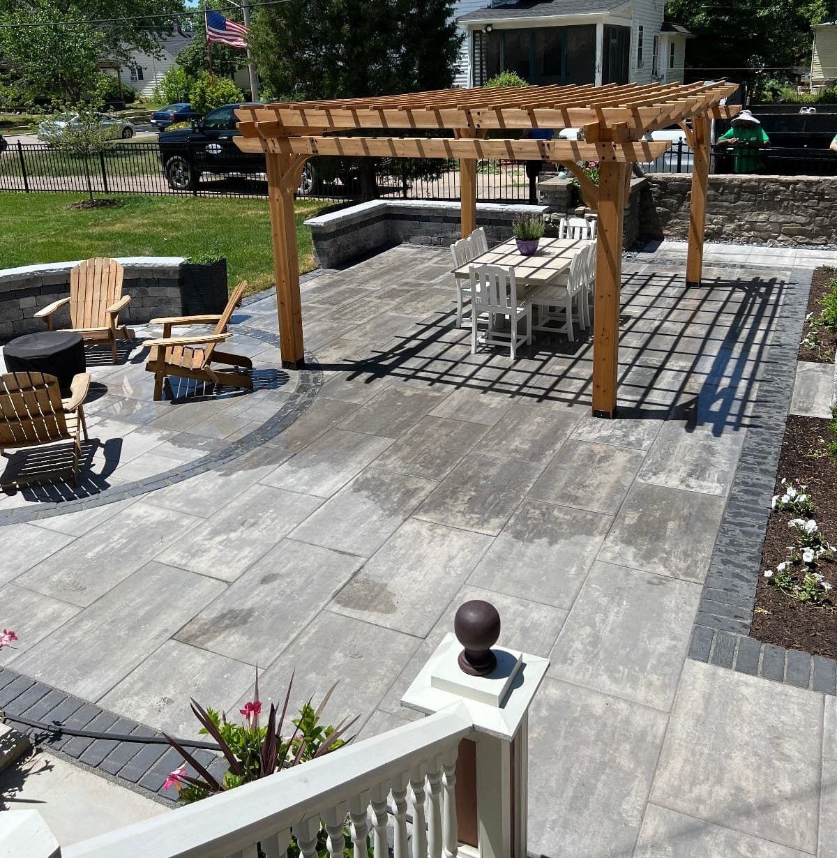 Patio with wooden pergola, gray pavers, table, chairs, and fire pit.