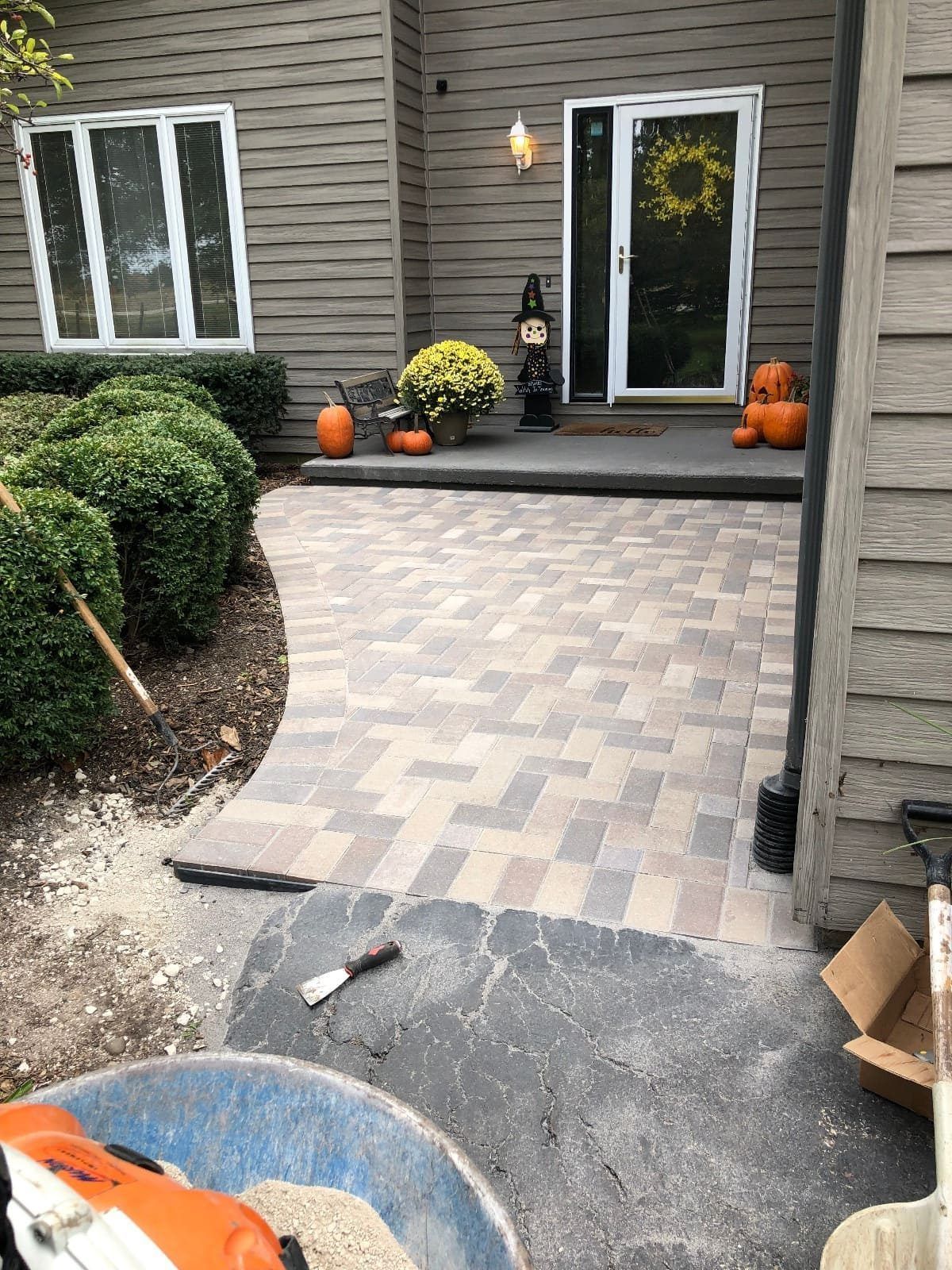 Brick pathway leading to a decorated porch with pumpkins and Halloween decor.