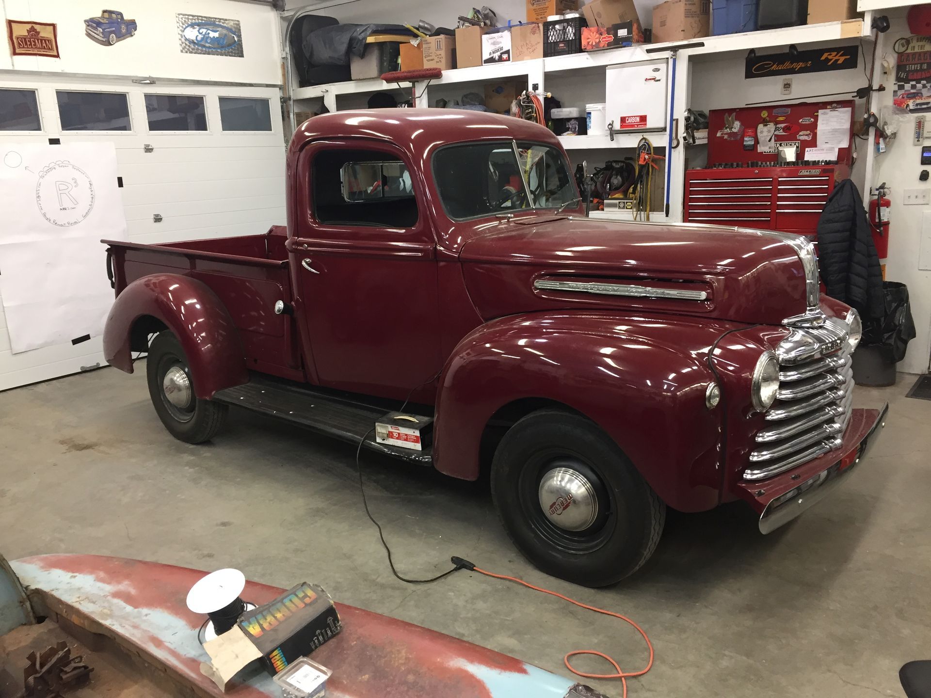 Dark red vintage pickup truck in a garage.