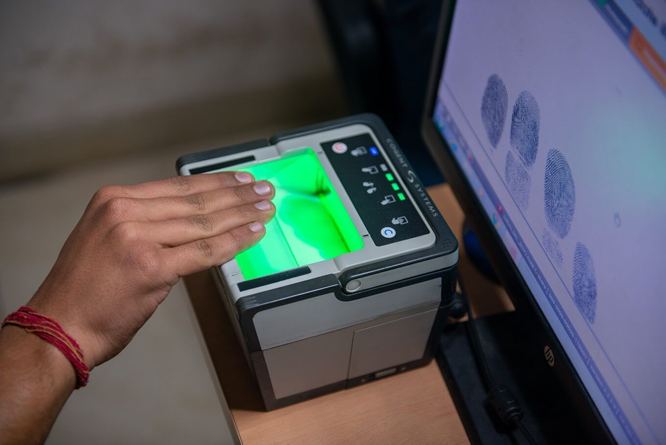 A person is using a fingerprint scanner in front of a computer monitor