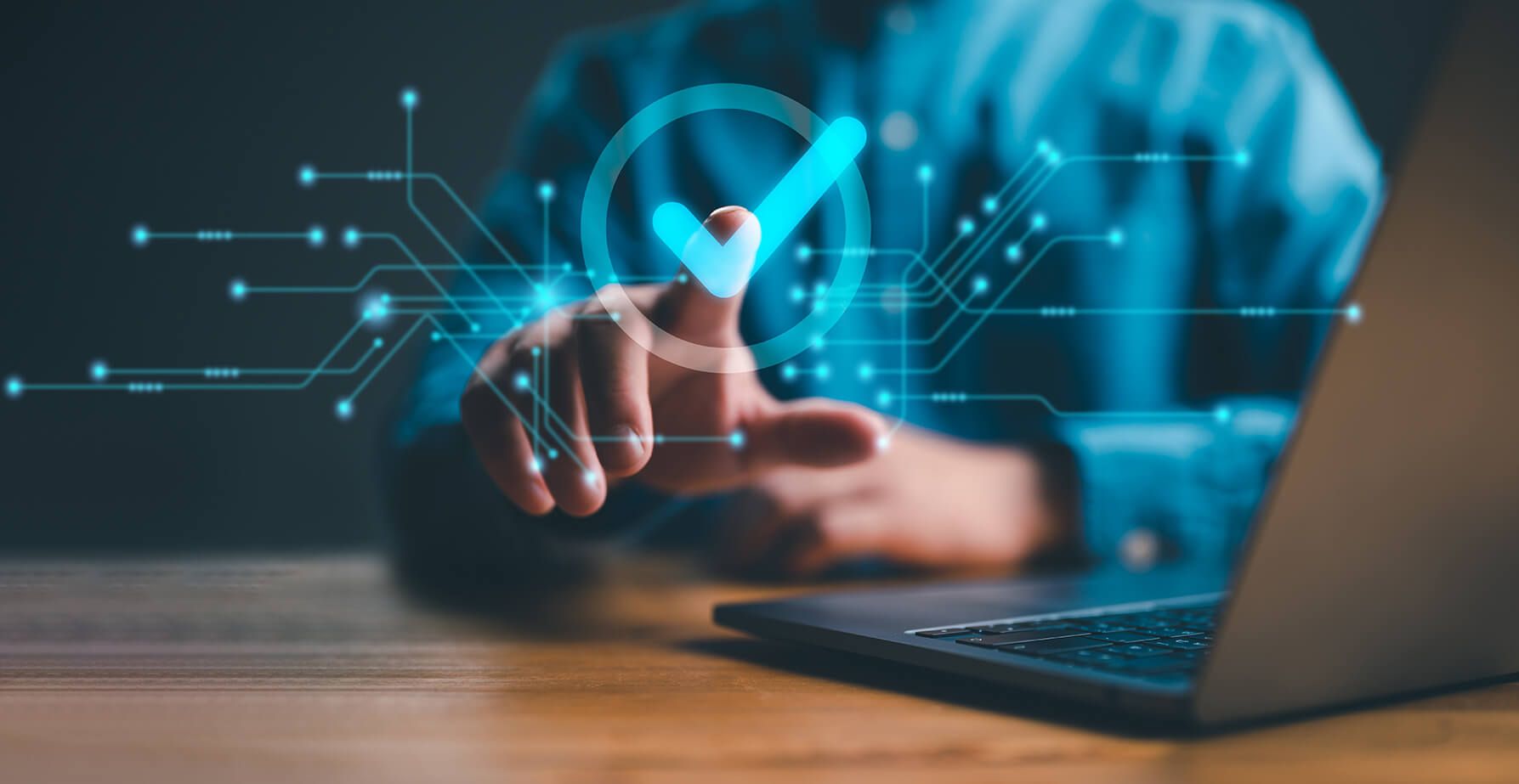 A person is using a laptop computer with a check mark coming out of their finger.