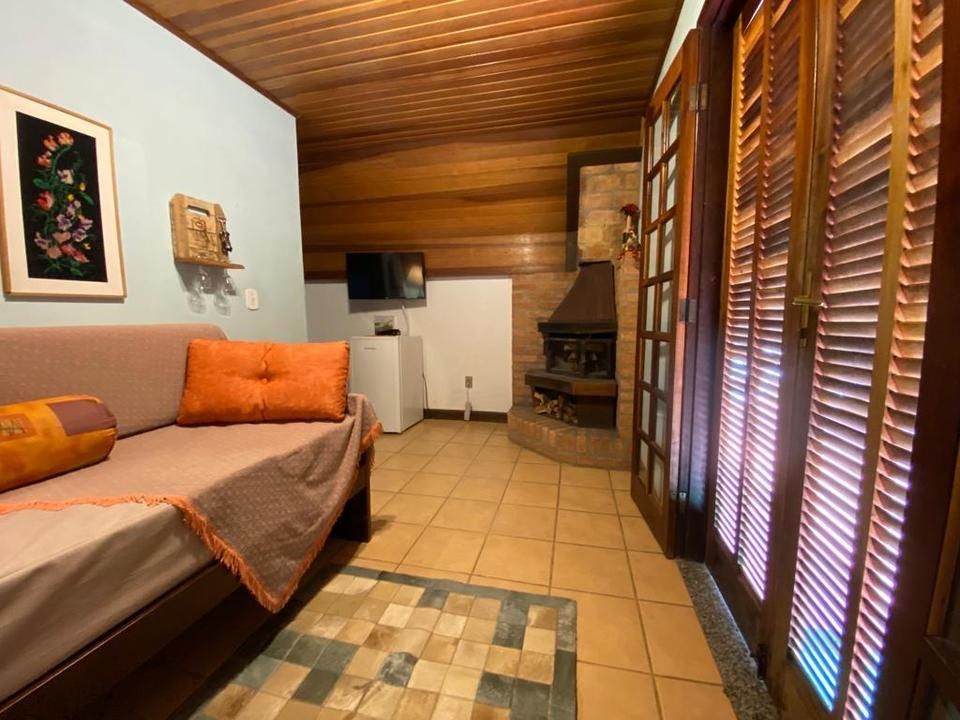 Sala de estar com sofá, lareira e portas de madeira com persianas.