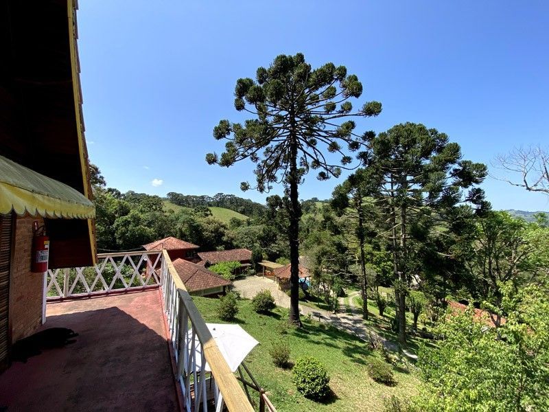 Vista de uma varanda com vista para uma paisagem rural com árvores, edifícios e um céu azul brilhante.
