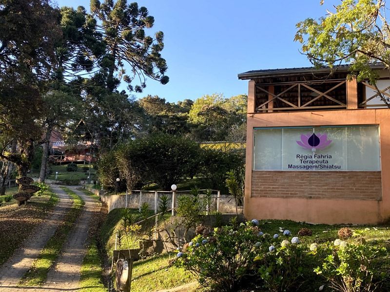 Prédio com placa indicativa e caminho que leva até ele, em um ambiente verdejante e exuberante.