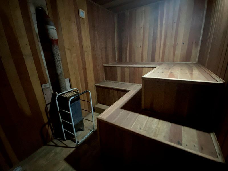 Interior de sauna de madeira com bancos e aquecedor.