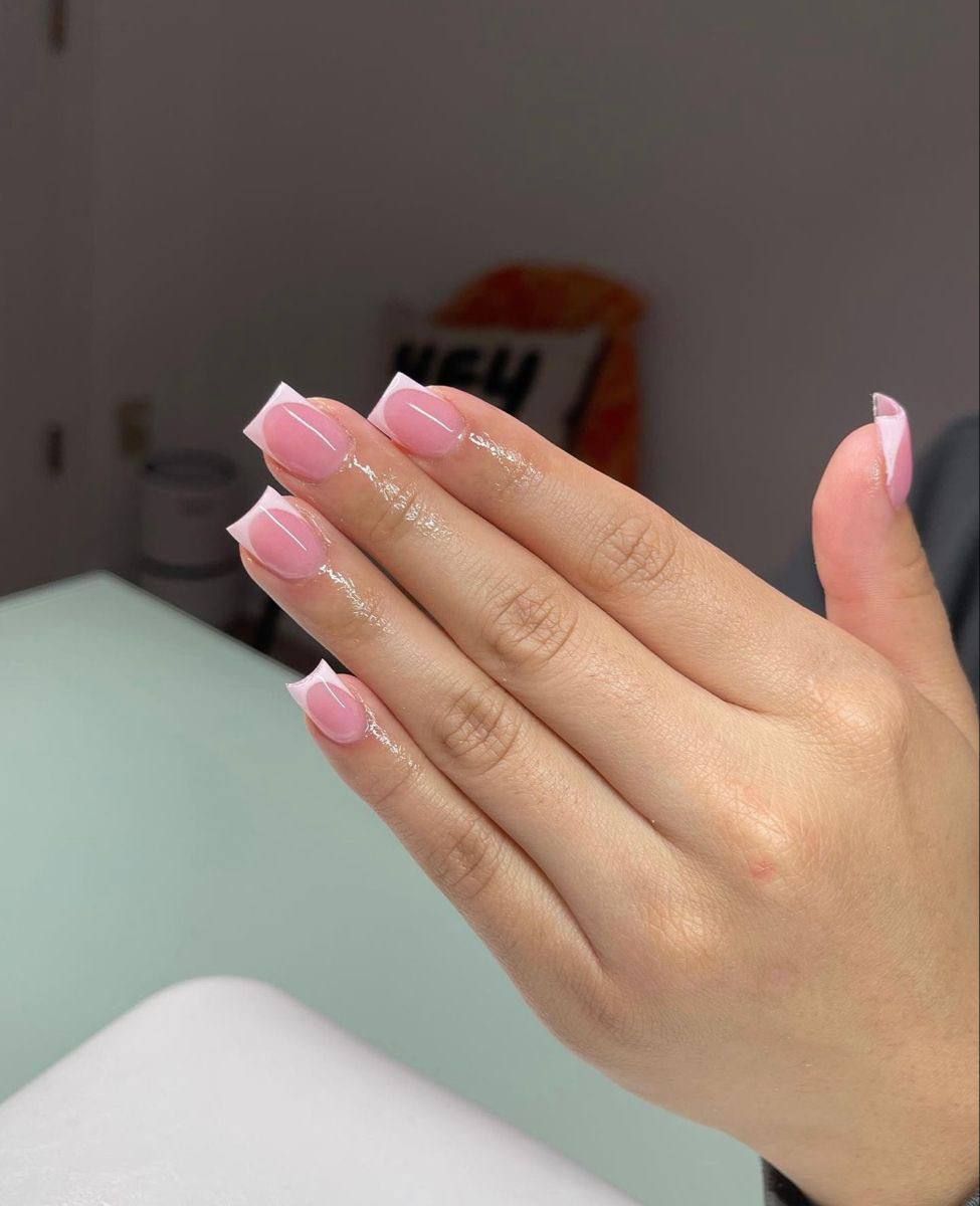 A hand showing a fresh manicure with a classic pink base and white French tips on square-shaped nails.