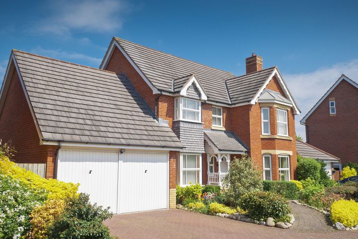 A large brick house with a gray roof and white garage doors