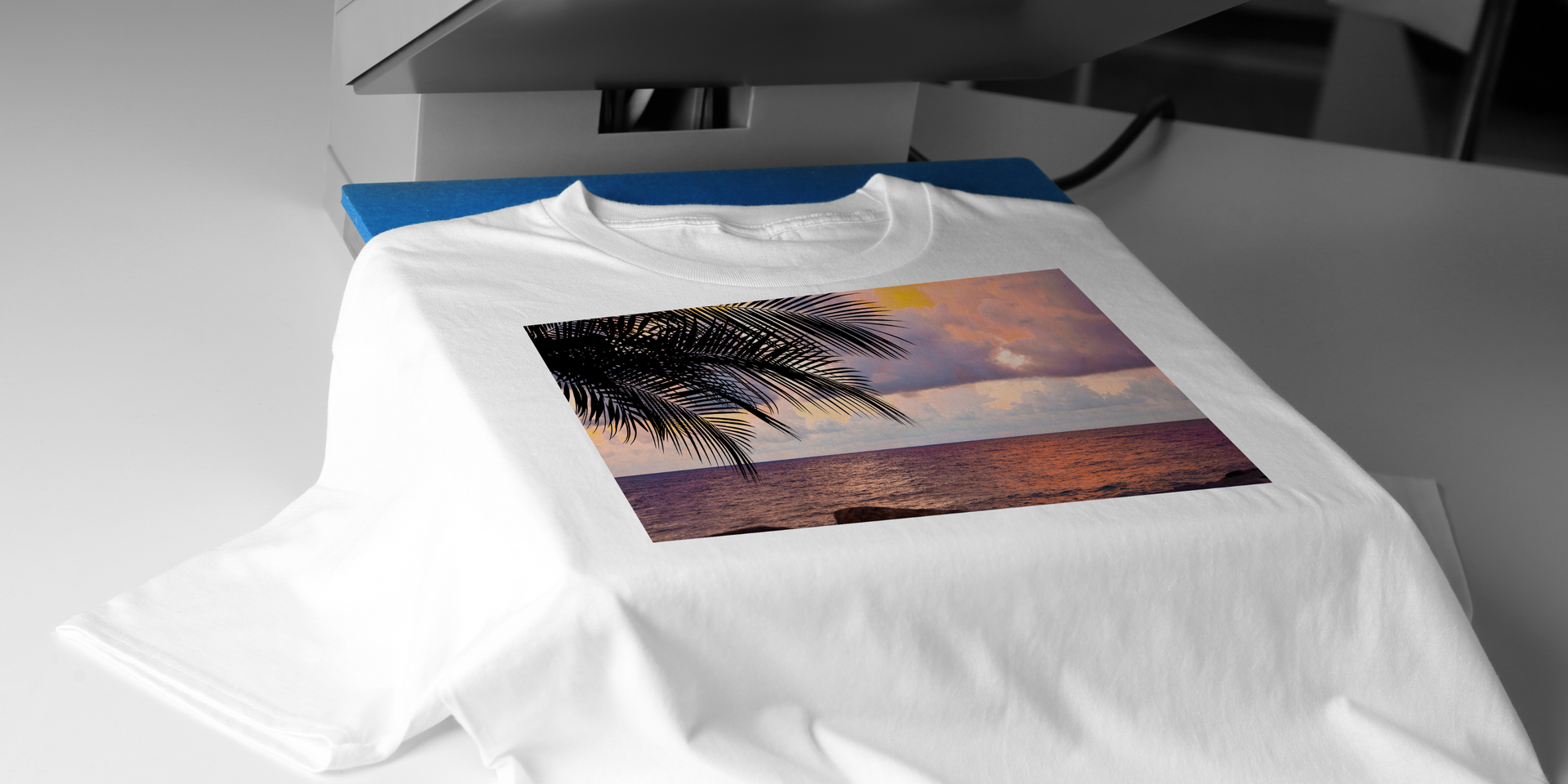 White t-shirt with beach scene print in a heat press.