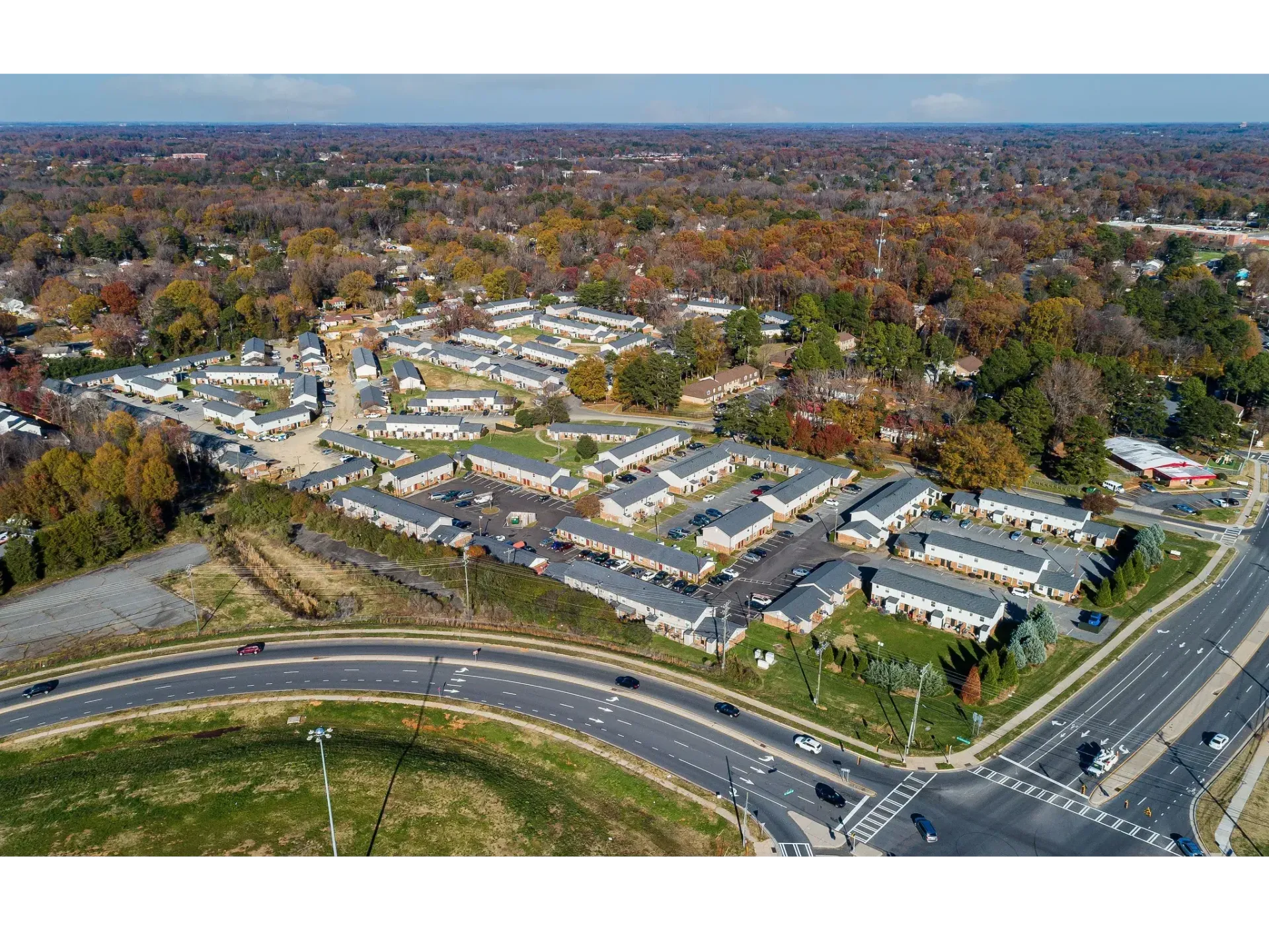 Aerial view of a suburban neighborhood with curving roads, houses, and autumn-colored trees.