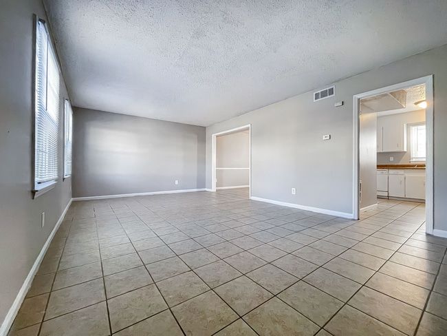 Open closet with white doors in a beige carpeted room near a doorway