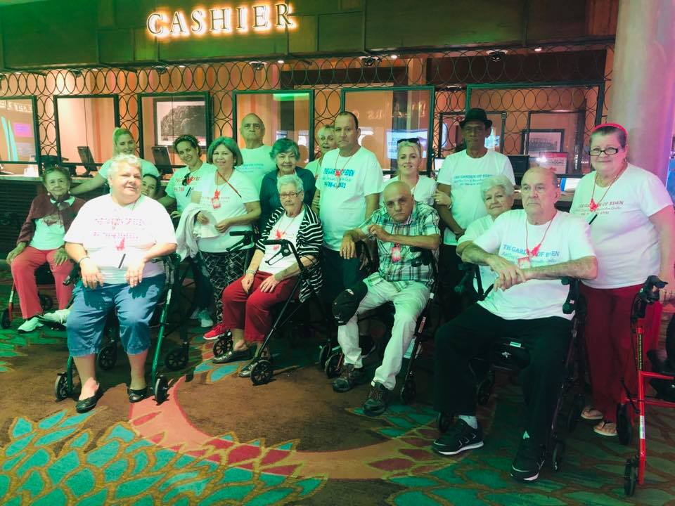 Group of people in wheelchairs and walkers at a casino cashier. Some wear matching shirts.