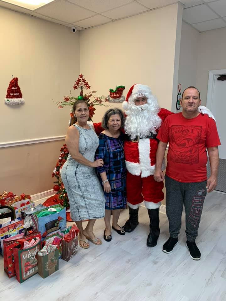 People pose with Santa near a Christmas tree and gifts.