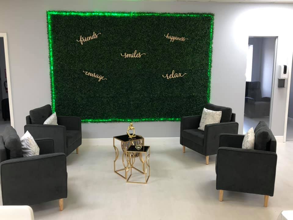 Lounge area with gray armchairs, a green wall, and gold accents. 