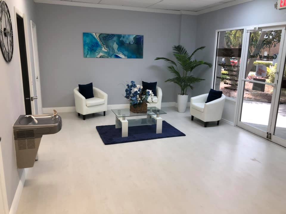 Waiting room with white chairs, blue accents, and a water fountain.