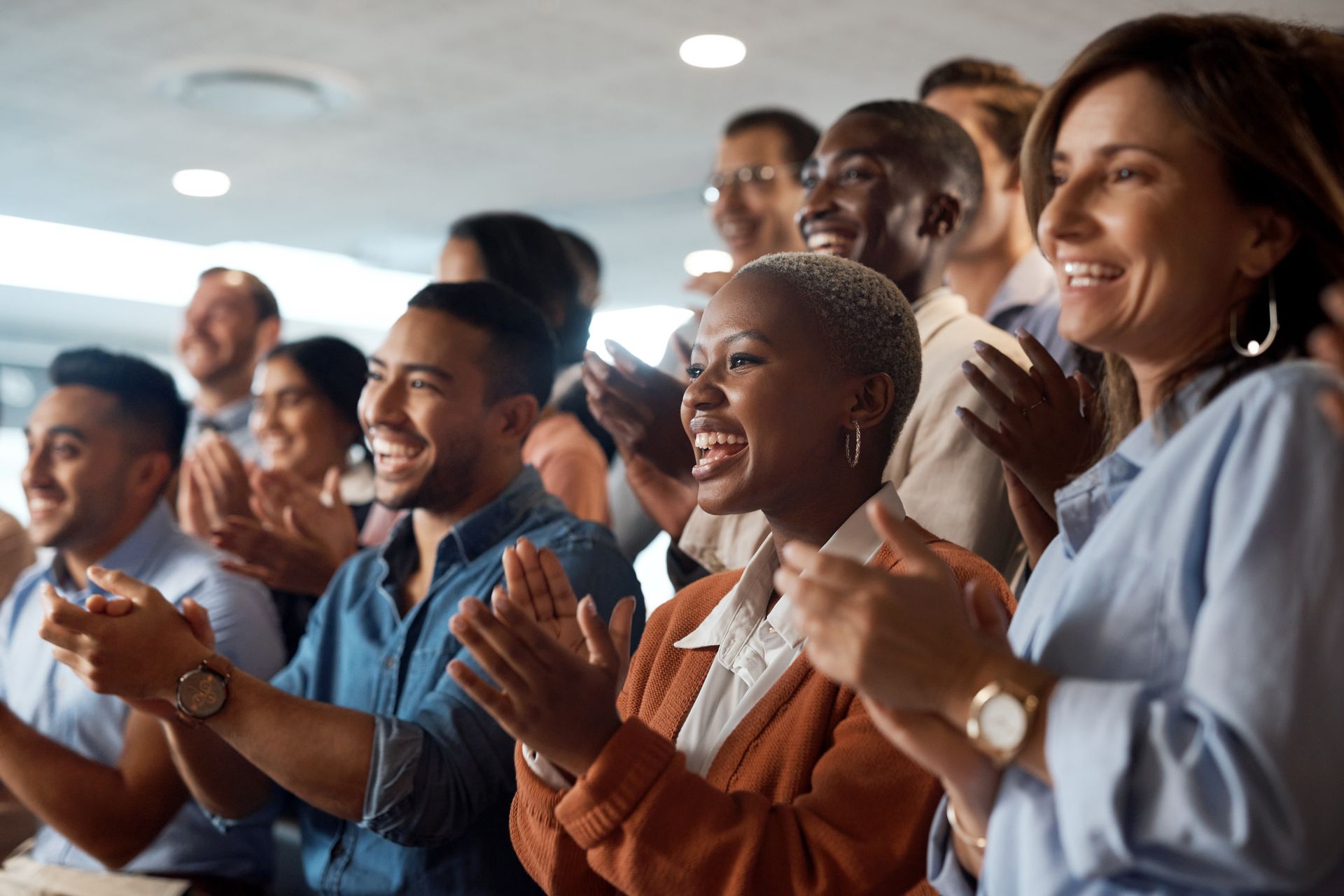 People of diverse ethnicities clapping and smiling in an office setting