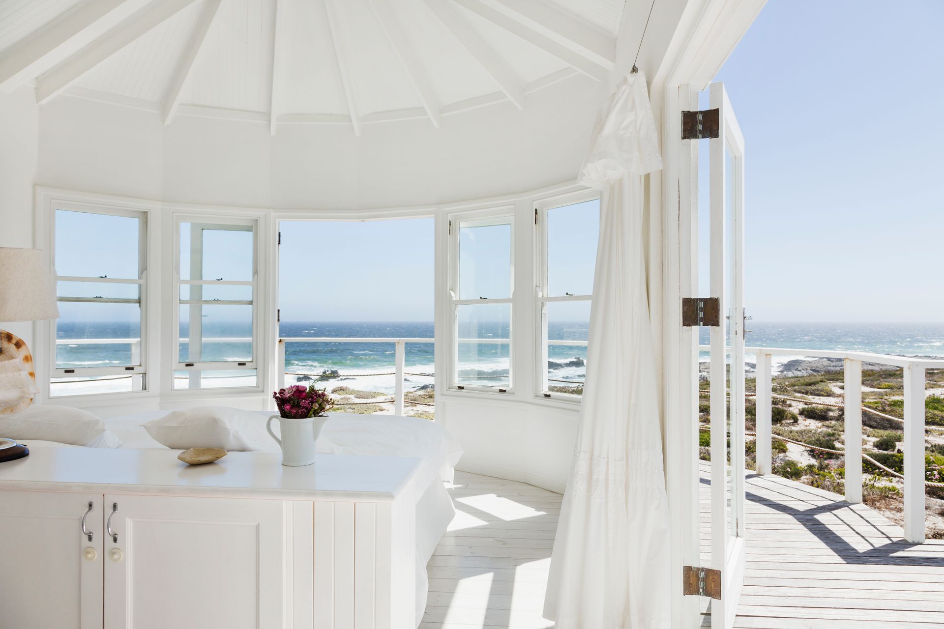 Bright white beach gazebo with ocean view and open curtains