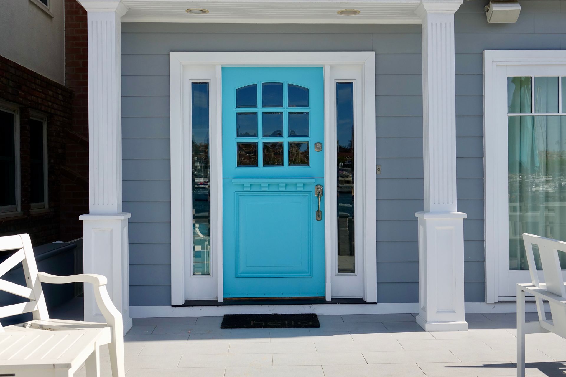 Blue front door with white trim and columns on a gray porch