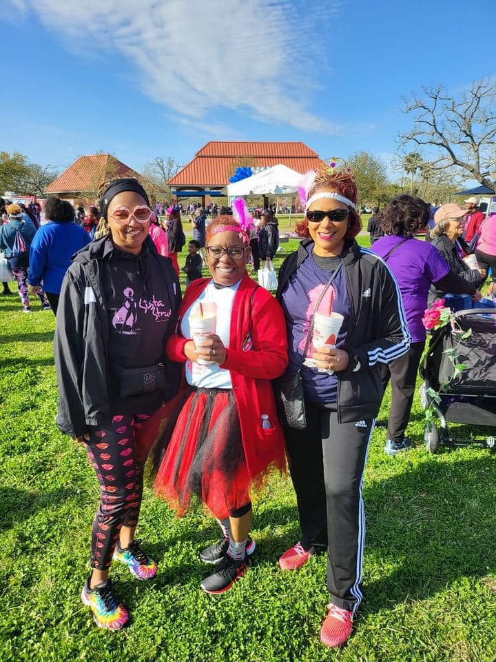 Three women are posing for a picture in a park.