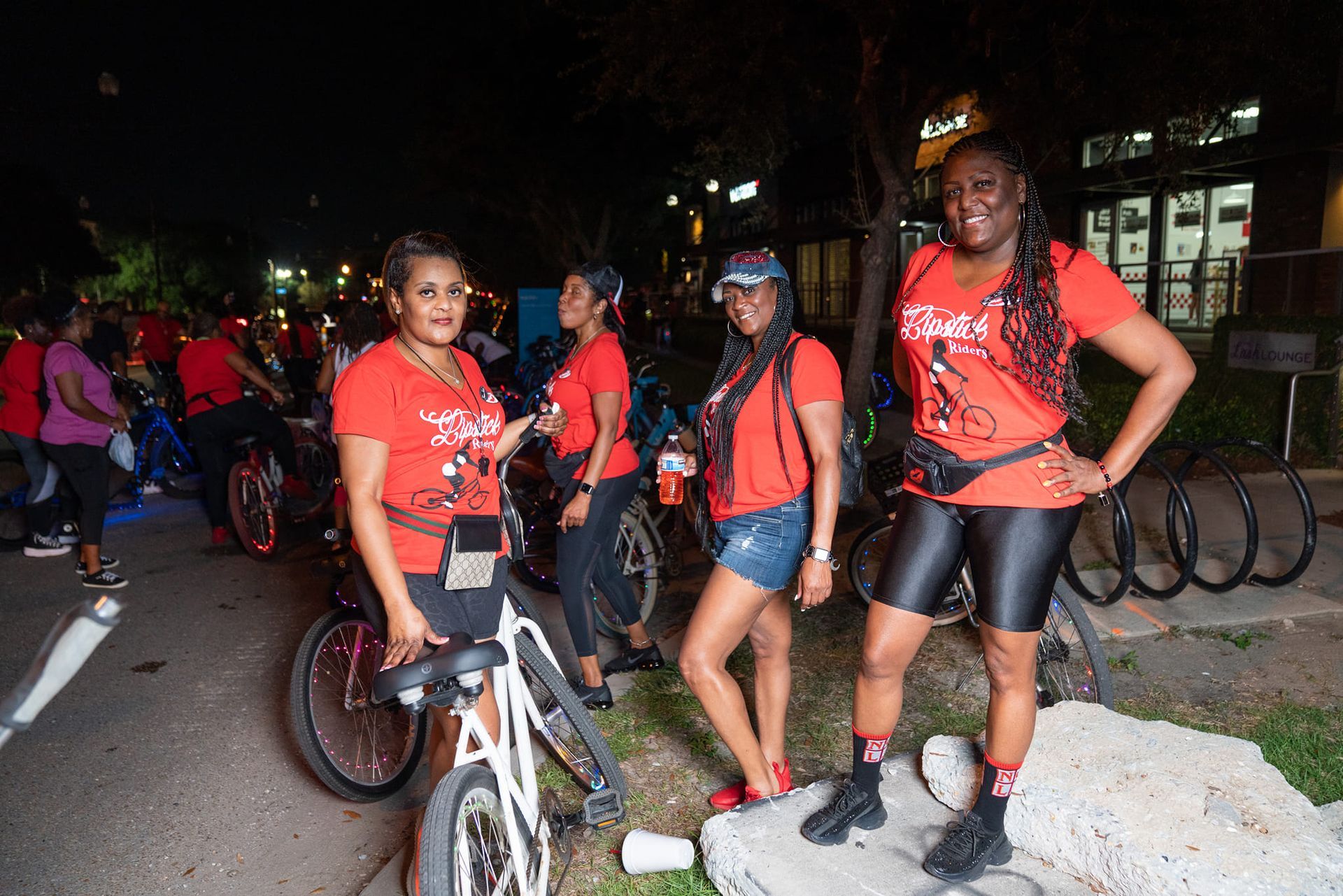 A group of women in red shirts are standing next to bicycles.