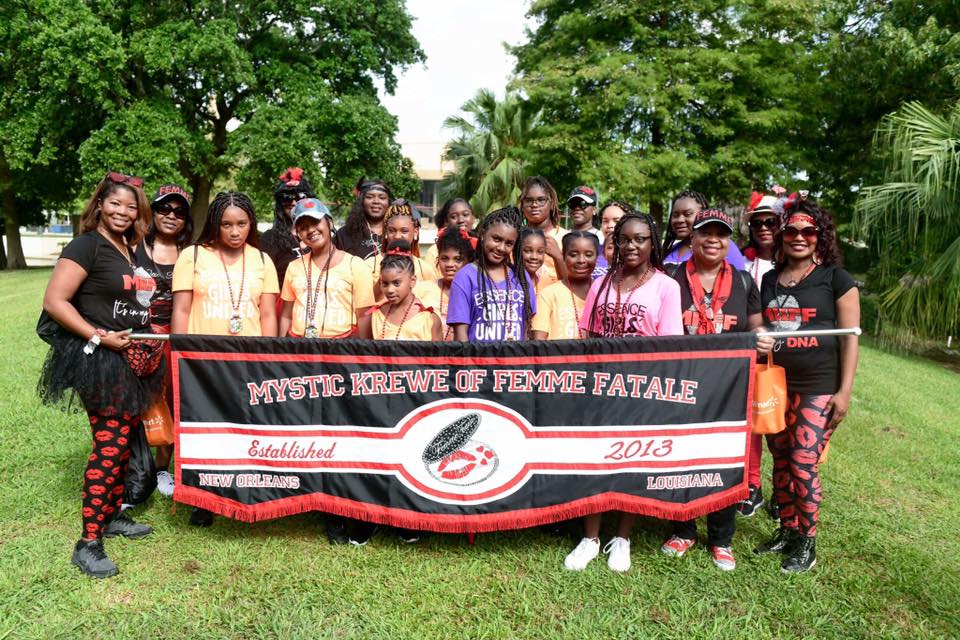 A group of people holding a banner that says mystic brew of femme fatale