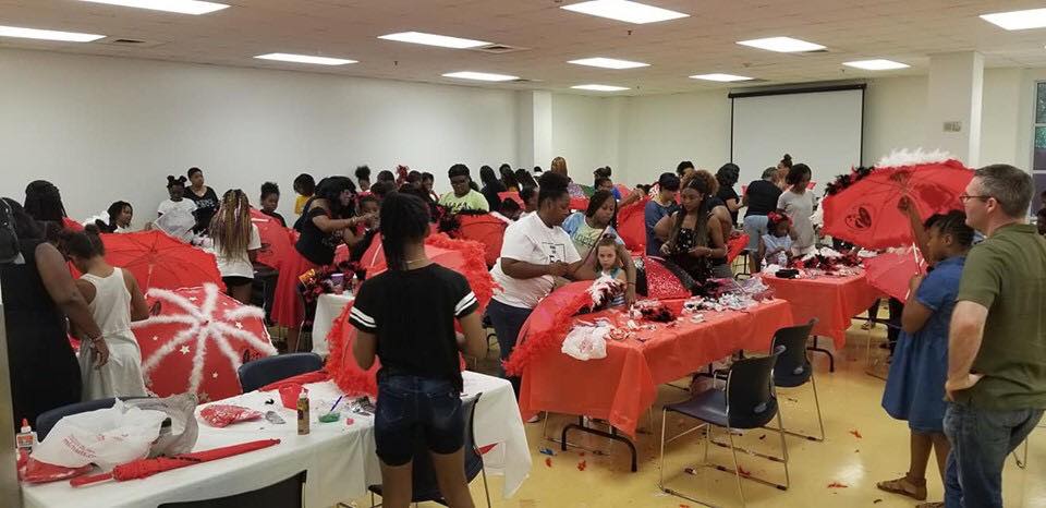 A large group of people are standing around tables in a room.