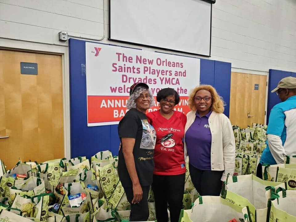 Three women standing in front of a sign that says the new orleans saints players and dryades ymca