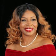 A woman is wearing a white fur coat and a pearl necklace.