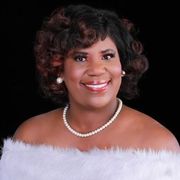 A woman in a red dress and pearl necklace is smiling for the camera.