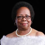 A woman wearing glasses and a pearl necklace