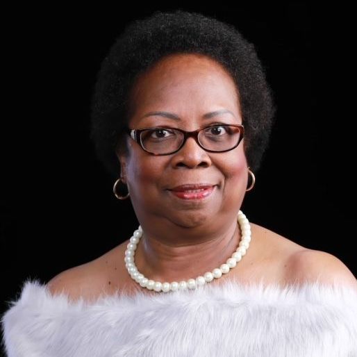 A woman wearing glasses and a pearl necklace