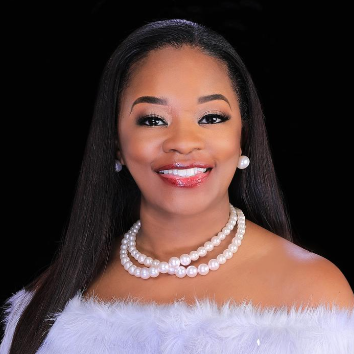 A woman wearing a fur coat and a pearl necklace is smiling for the camera.