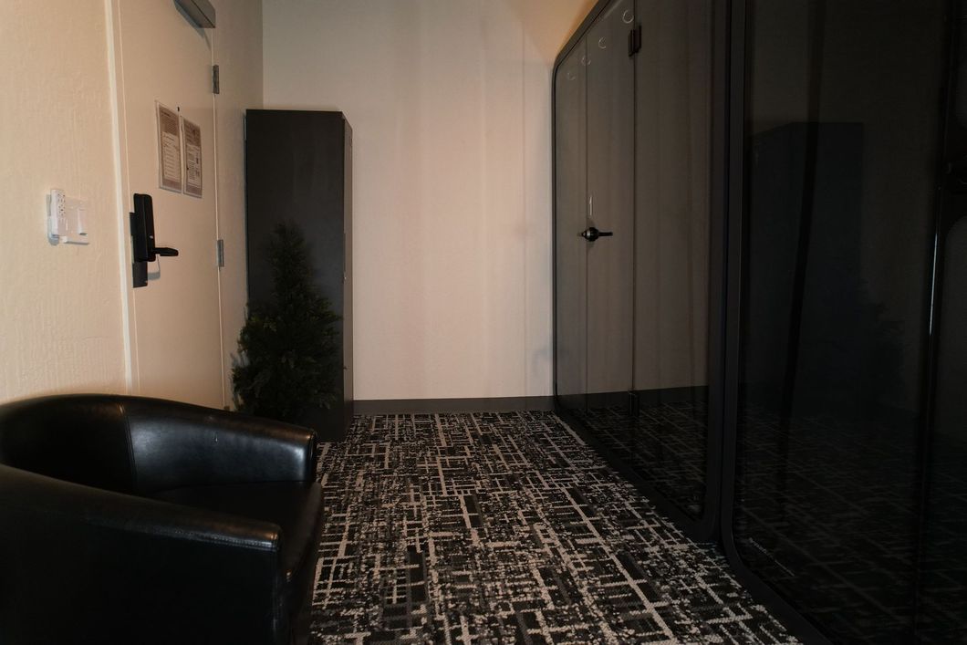 Interior hallway with black door, armchair, and carpet.